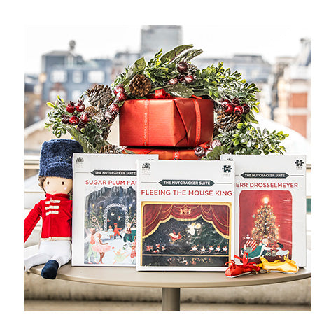 Three jigsaw puzzle boxes propped against a stack of wrapped red gifts.