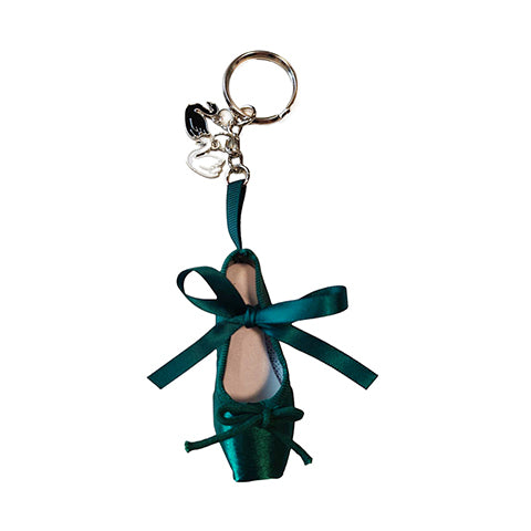 An emerald green miniature point shoe on a keyring with two swan charms attached.