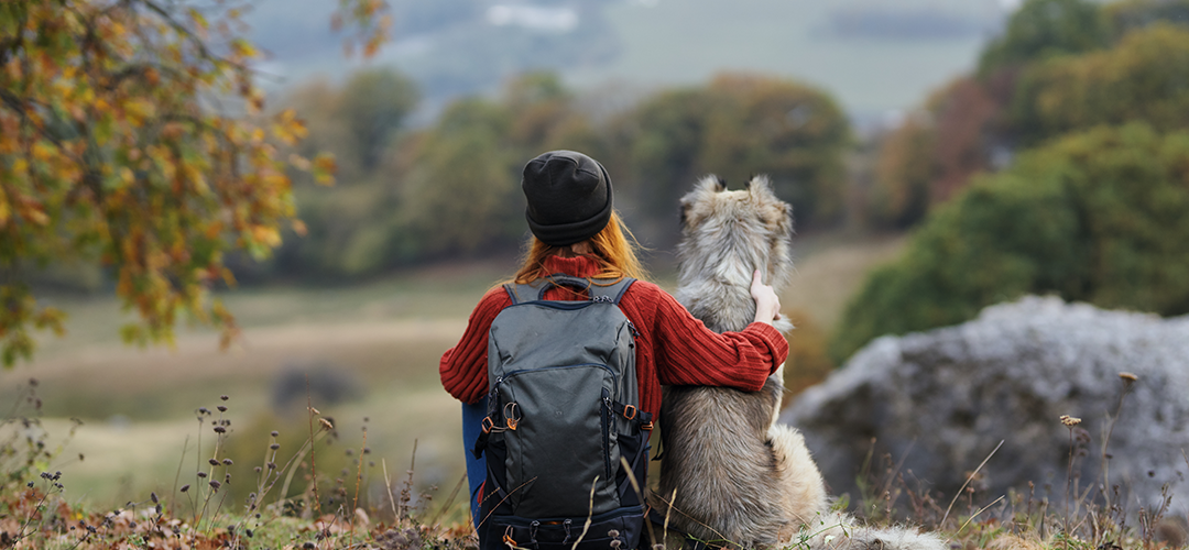 Woman sitting with a dog looking across a local park