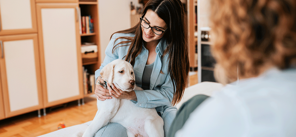 Woman holding a white support dog in an apartment