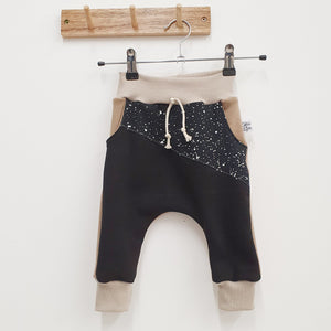 bayridgecaskandkeg children's jogging bottoms. Made with black and beige sweat, beige cuffing fabric waistband and cuffs and a black splatter printed accent panel across the front. 