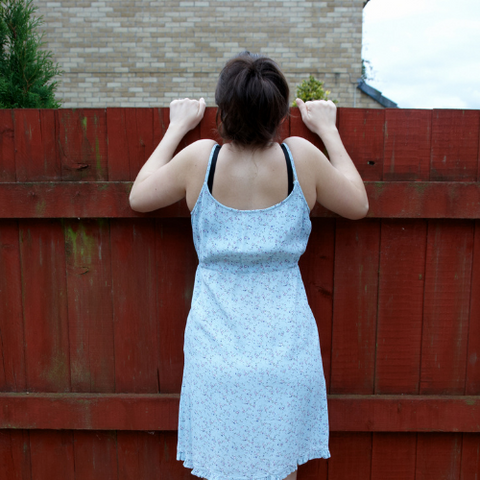 Woman struggling to look over top of garden fence into her neighbours garden