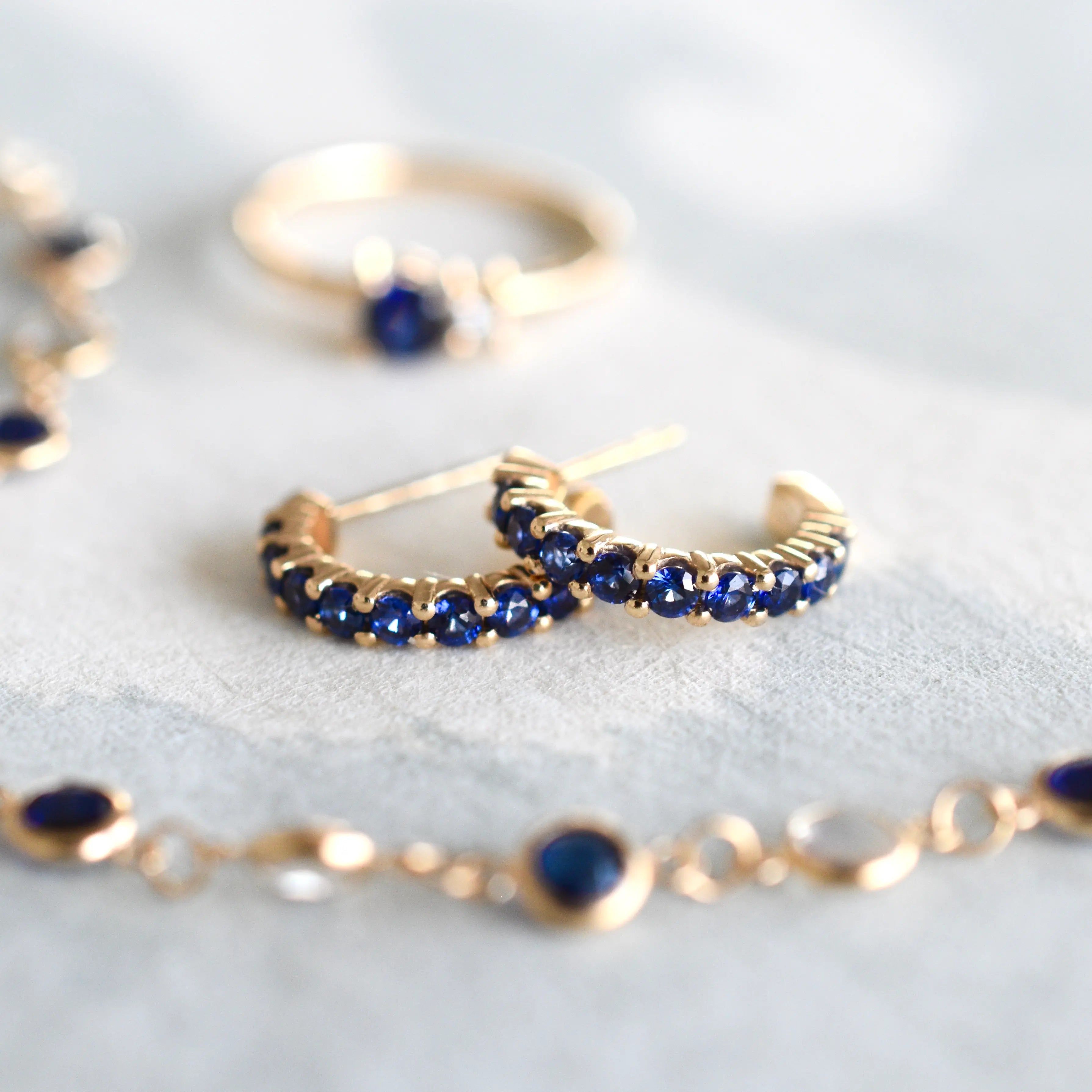 Gold and sapphire jewelry set on a light background.