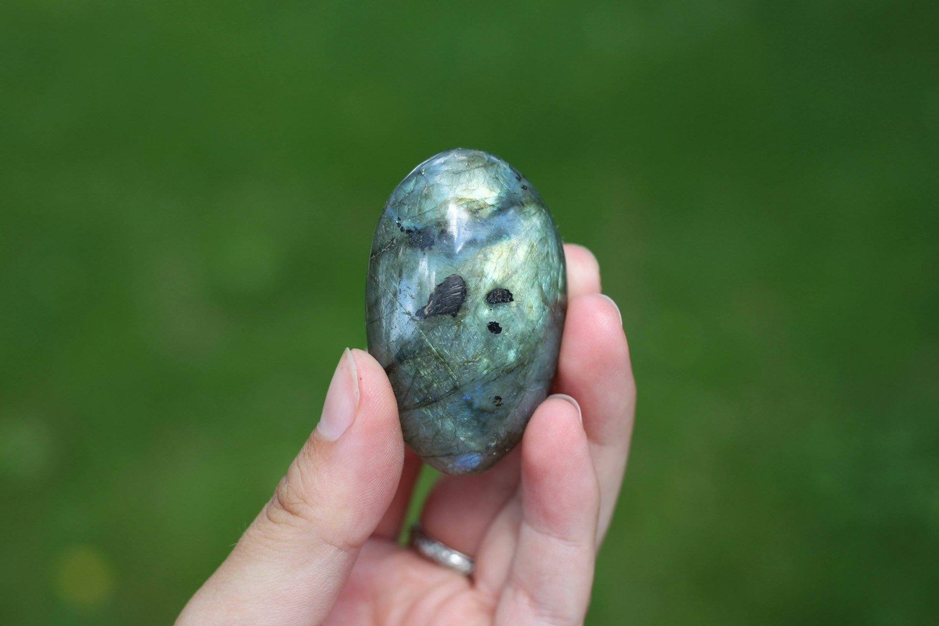 A close-up of someone holding up a piece of Labradorite