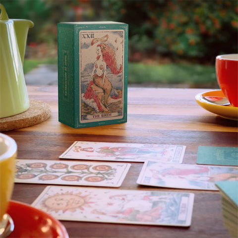 Tarot of Musterberg box and cards on wood table with tea pot and cups