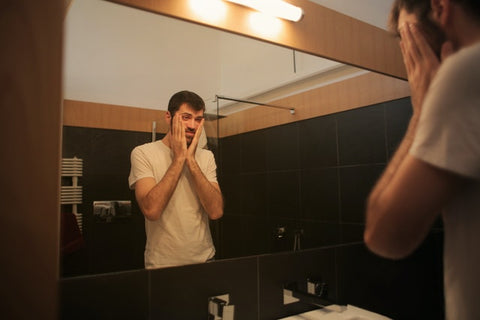 hombre con migraña frente al espejo