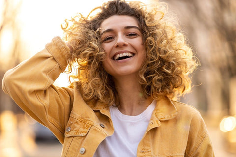 Young woman running hands through curls, smiling 