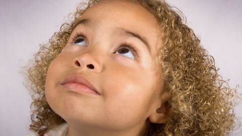 Young mixed girl with curly coily blonde brown hair looking up
