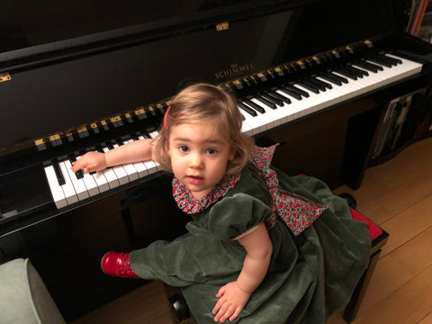 Chiara at the piano in her Fir green smocked dresss with Liberty details! Precious