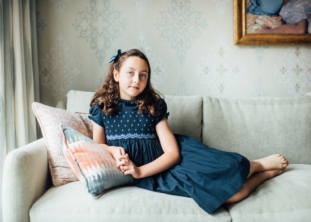 Child in smocked dress sitting on a sofa portrait