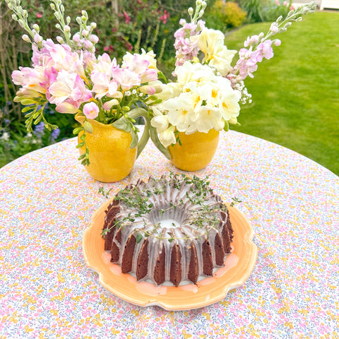 Bundt cake on a orange plate in garden with flowers in baackground