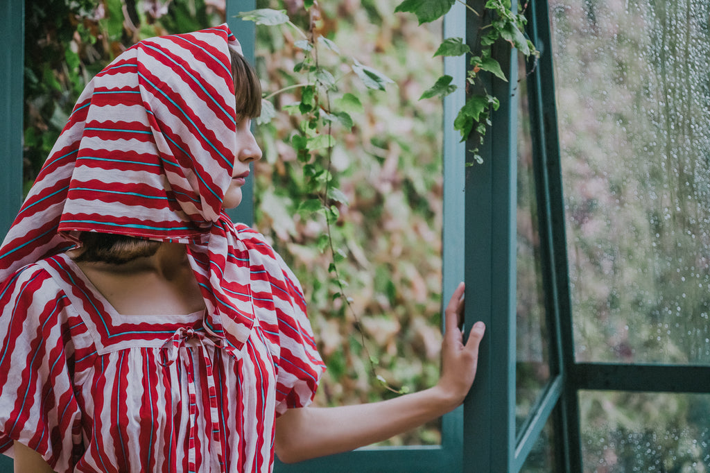 Rosie stands looking out window wearing Picnic pieces from Little Tienda