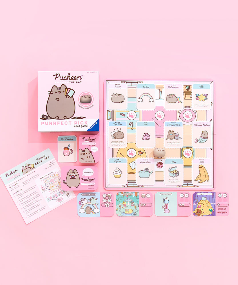 Overhead view of all of the card game contents laid out neatly on top of a pink floor. The board has three rows of four essentials cards, featuring items such as cupcakes and characters such as Sloth, with the mini Pusheen figurine in the middle. Underneath the board are four Snapshot cards, featuring illustrations such as Dragonsheen on a pile of gold on the left side of the card and the essential cards necessary to pick up the Snapshot card on the right side. 