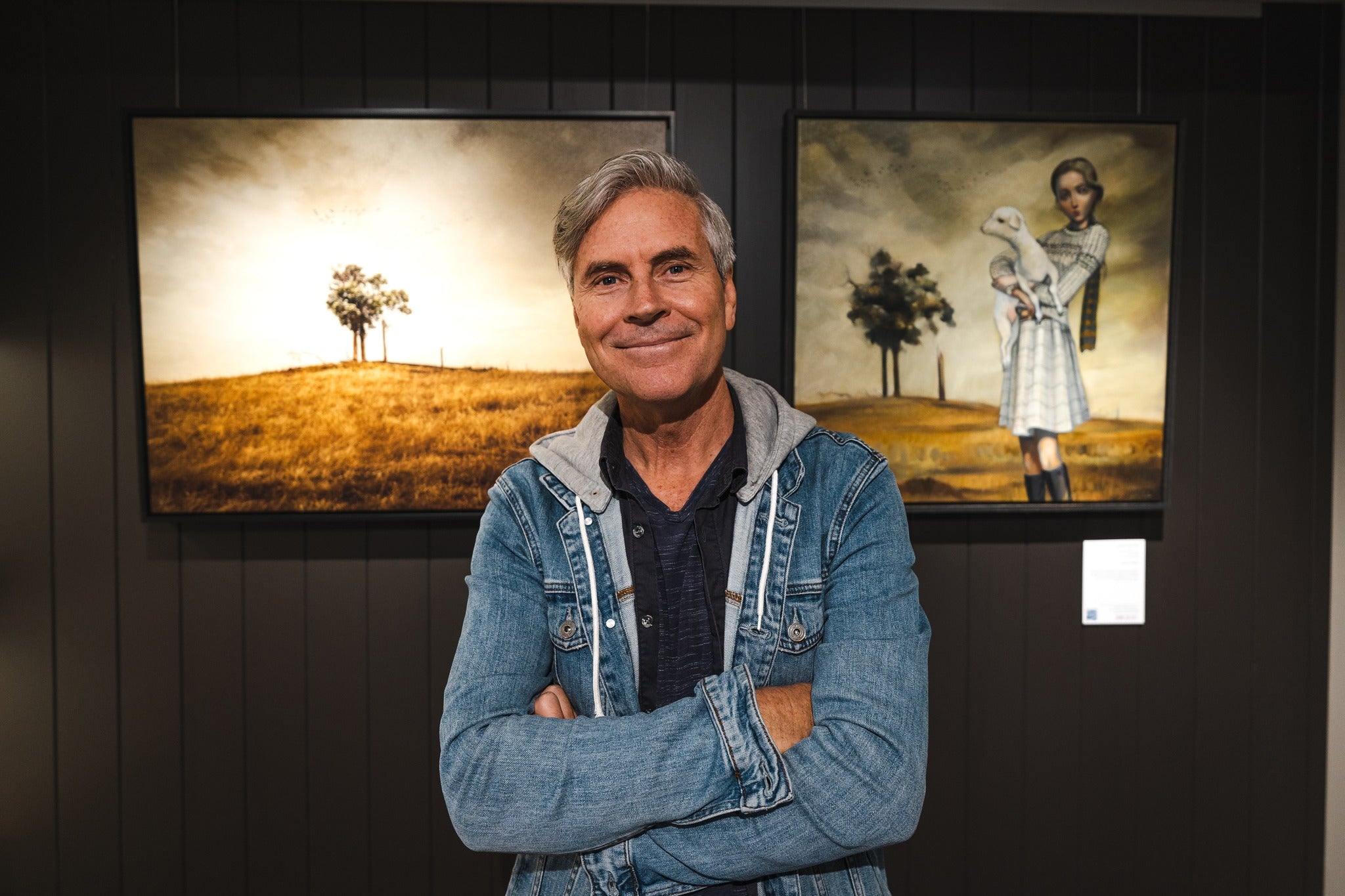 Christian Fletcher photographer in front of his image and a painting by Lauren Wilhelm in a collaborative exhbition.