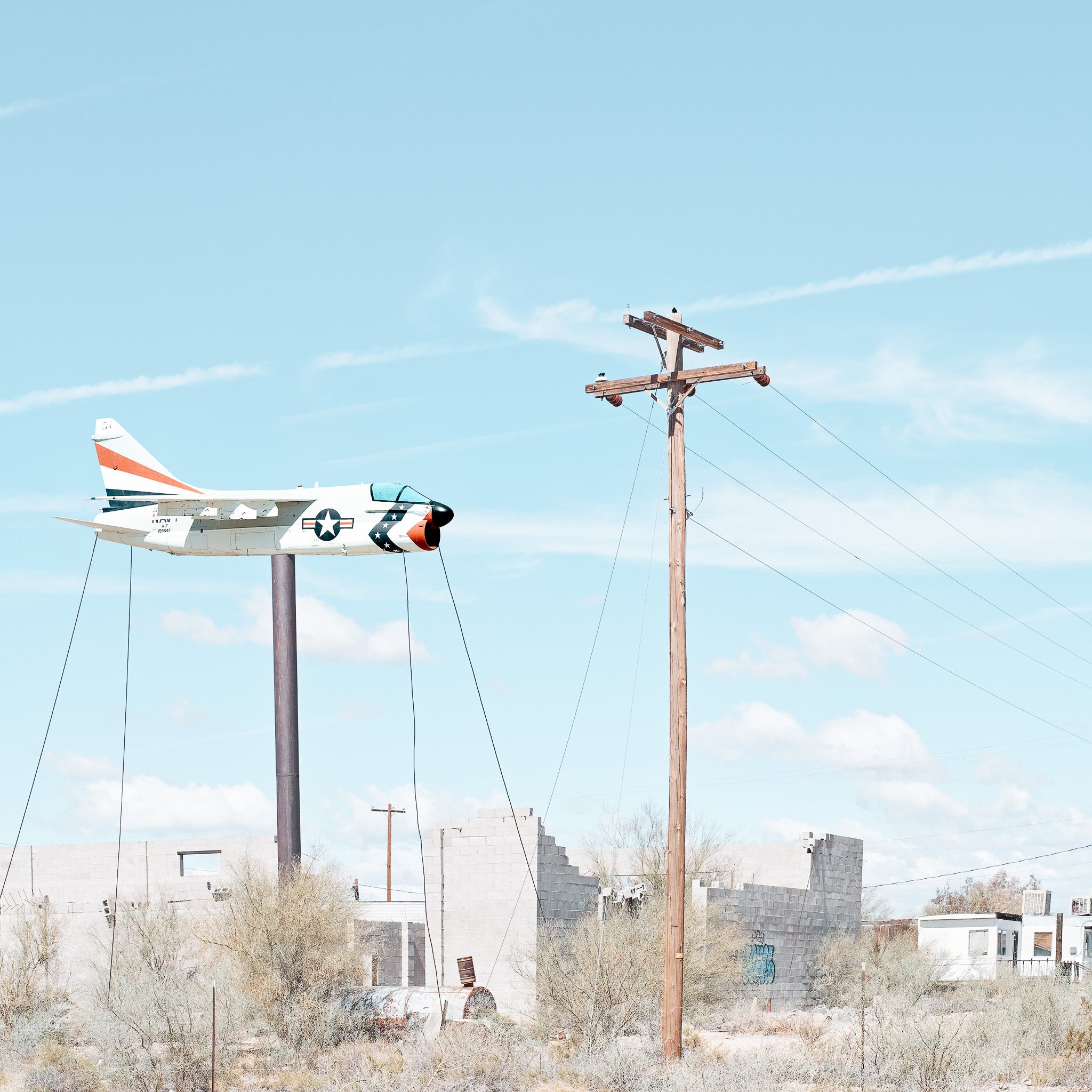 photograph taken in America of a fighter jet on a pole in a dusty town.