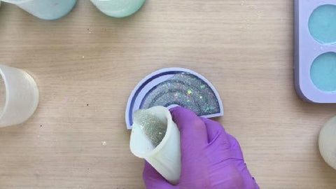 pouring glittery resin mix into rainbow silicone mold
