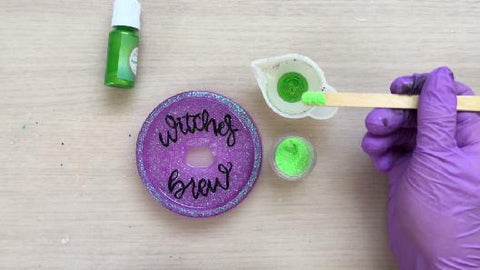 adding green glitter to the mixing cup