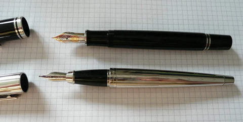 Two S.T. Dupont Ellipses pens set on a sheet of graphing paper. The caps are open to reveal a dutone gold nib and a palladium plated gold nib