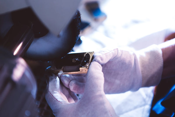 A pair of hands wearing white gloves carefully polishes an s.t. dupont luxury lighter.