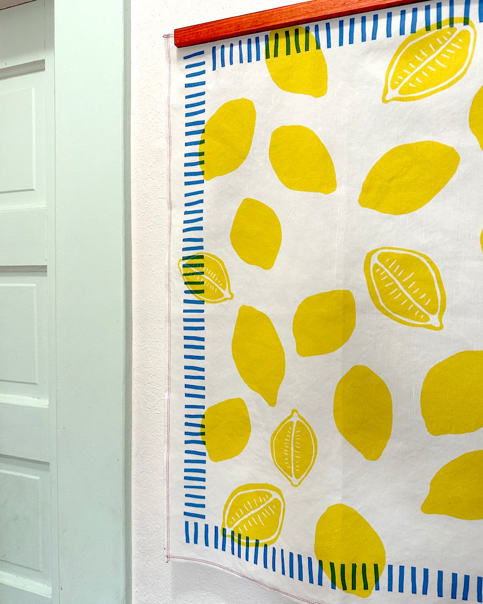Framed tea towel art hanging on a bright kitchen wall