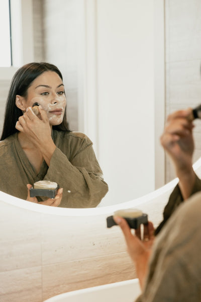 Zoe Sanders in mirror applying Collagen Cleanse with Kabuki Brush | Adashiko Collagen | 100% Natural Skincare