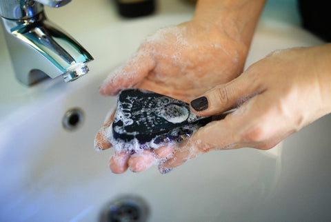 washing hands with ouija planchette soap at bathroom sink