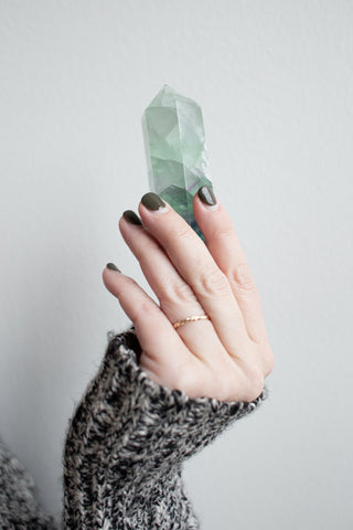 fluorite generator cut crystal in hand with cosy jumper and brown nails
