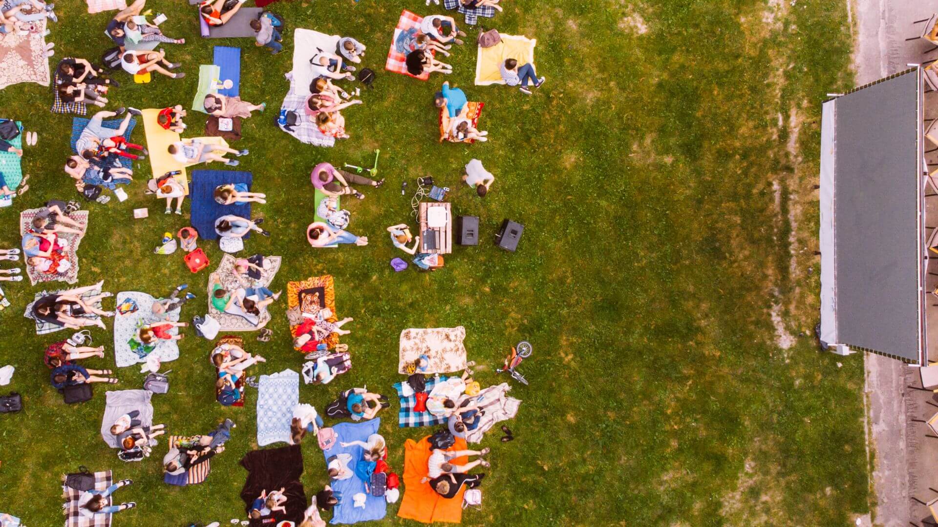 Viele Menschen sitzen auf Decken im Open-Air-Kino