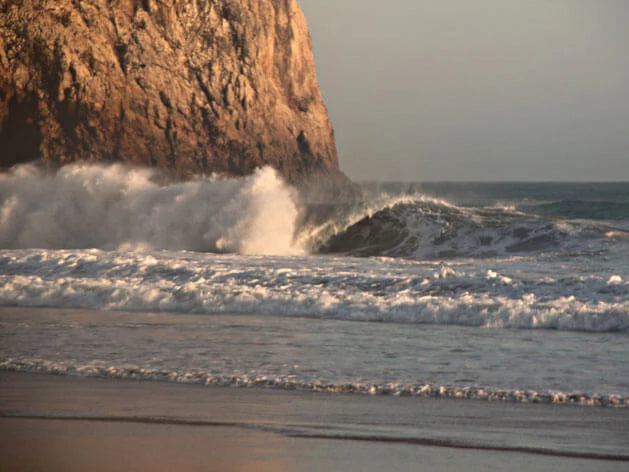 Welle bricht am Strand von Beliche in Portugal