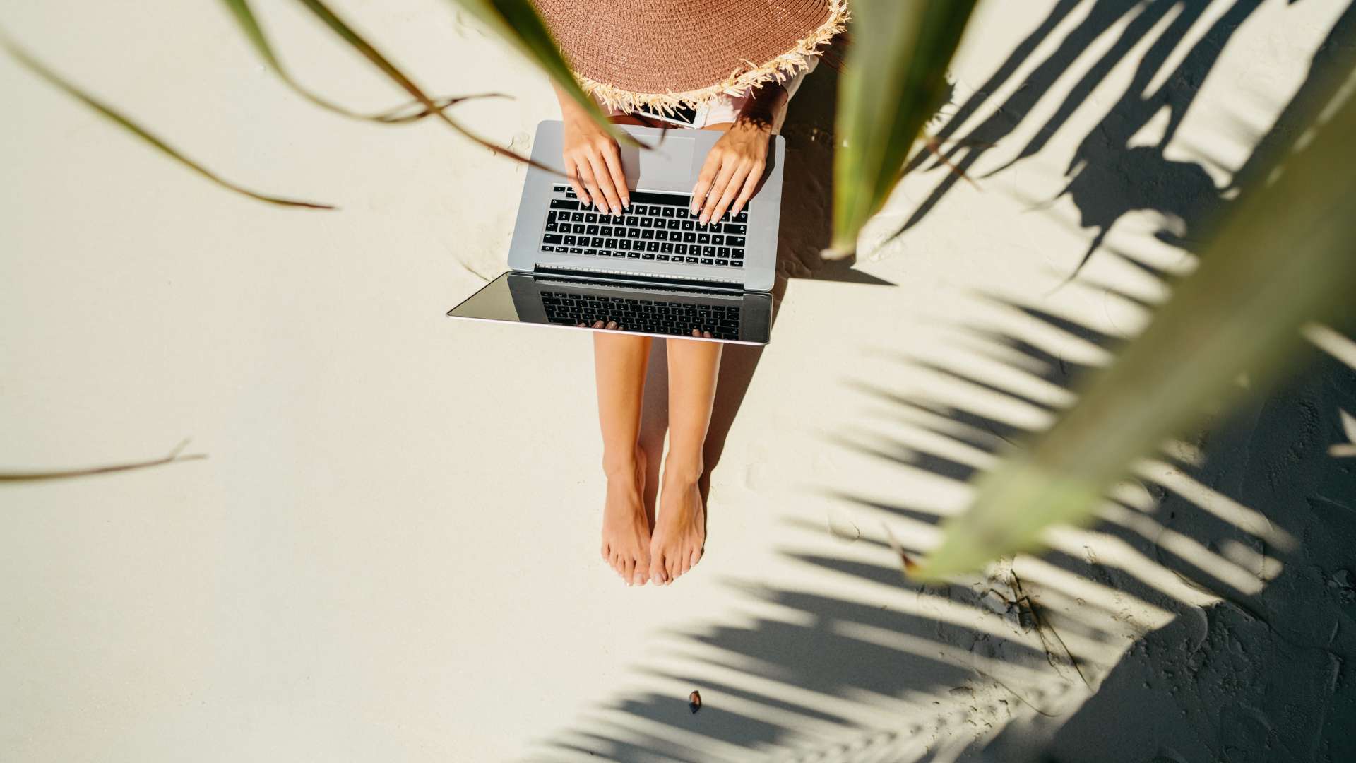 Das Klischee von New Work: Frau arbeitet am Schreibtisch am Strand