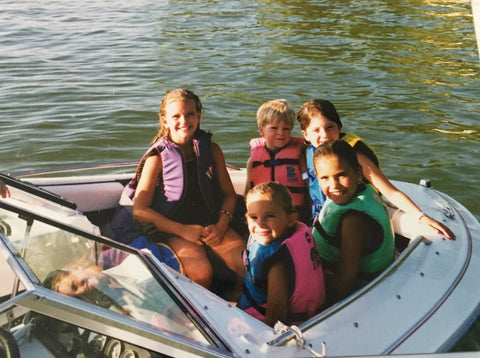 kids sitting on a boat with life vests