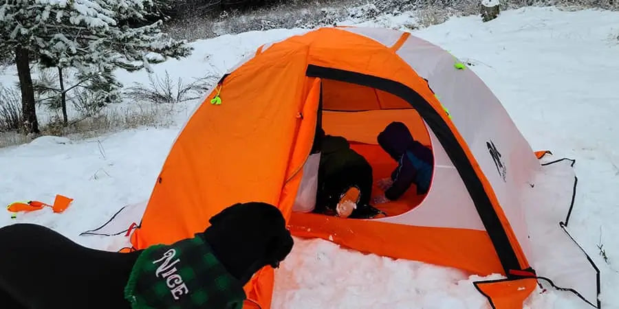 Orange 4 season tent with person inside with a dog