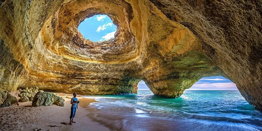 man standing in a cave with internal lake and hole in cave ceiling