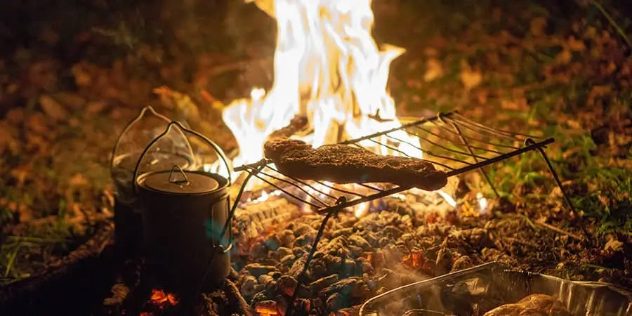 Cooking a steak in the campfire while it is burning