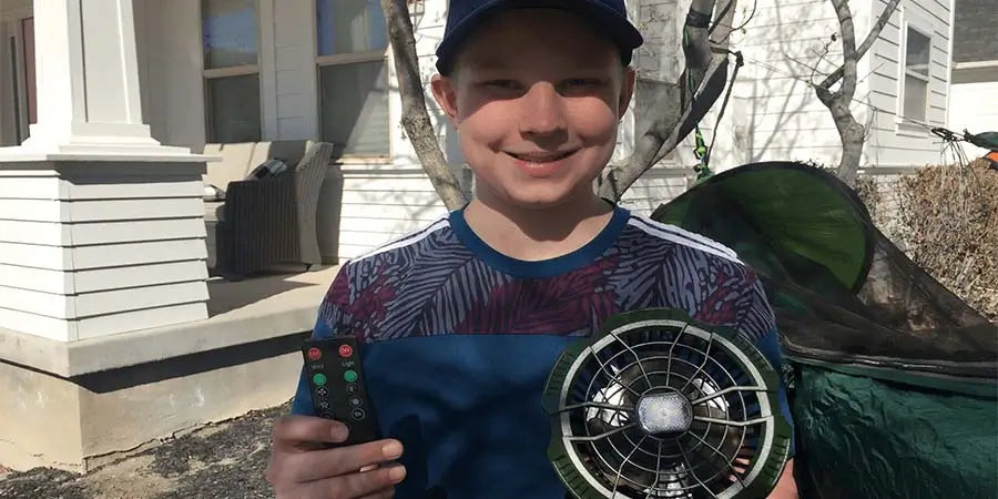 Kid holding a tent fan and remote