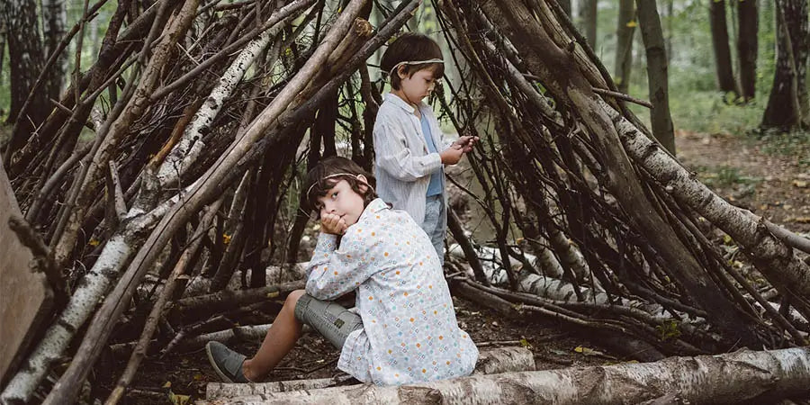 Two kids sitting inside a wooden fort