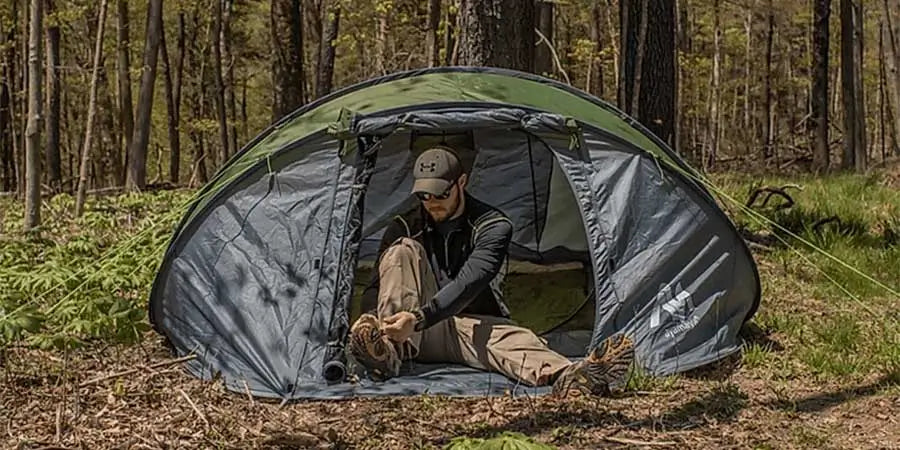 Man in a pop up tent within the forest