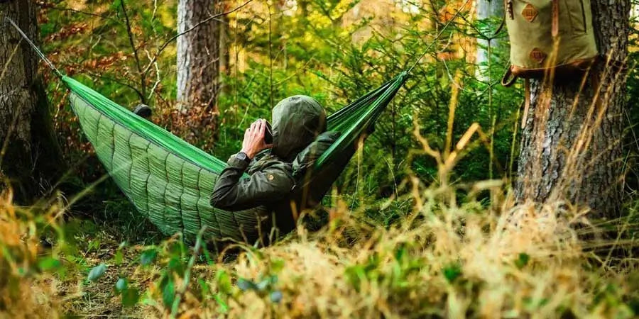 Man in green jacket lying in green hammock