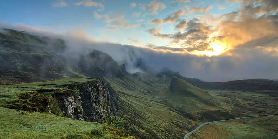 Green hillside with cliffs and fog