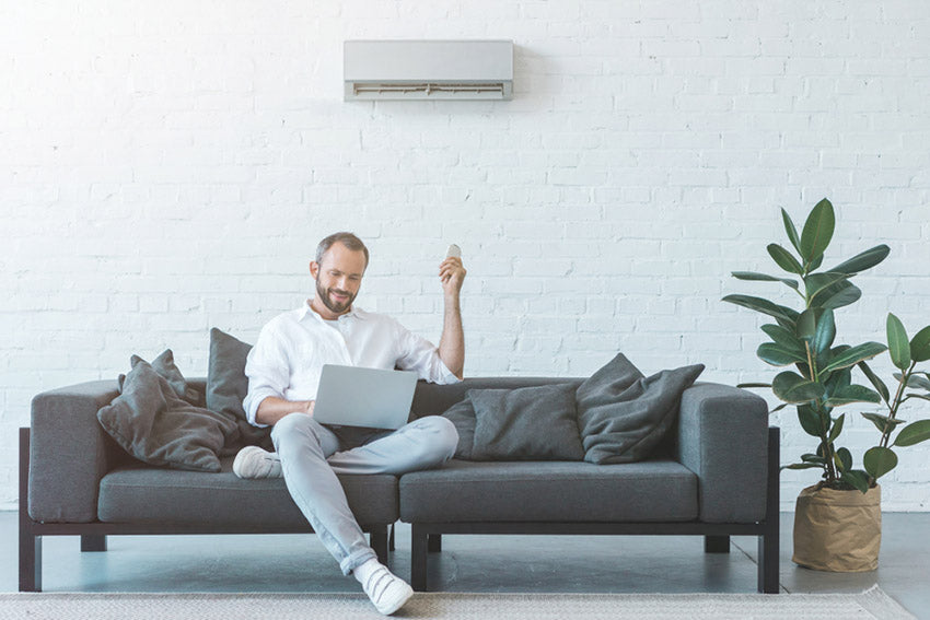 man turning on air conditioner with remote