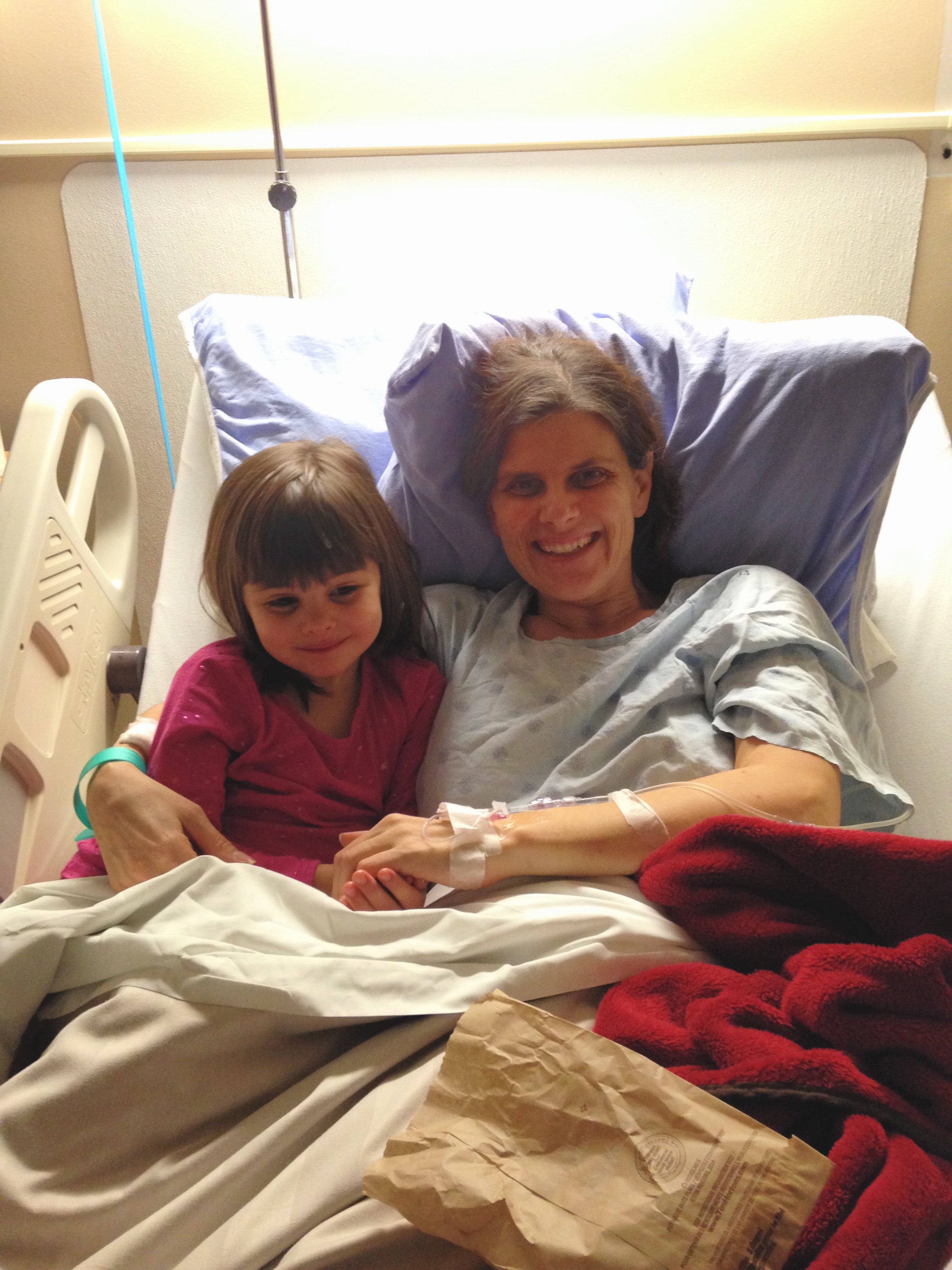 Julie in a hospital bed with her daughter cuddles beside her