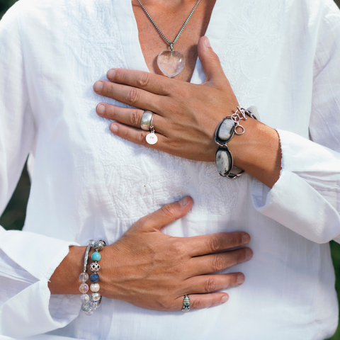 woman with her hands on her chest in a white top