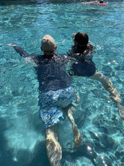 Colour photo of white adult male and white 11 year old girl, swimming away in a swimming pool