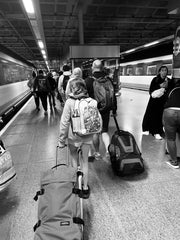 Black and white photo of girl and male, pulling suitcases along a platform at St Pancras station