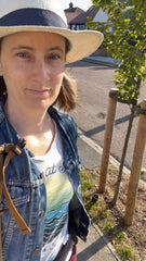 Colour photo of a white female in her 40s, wearing a white t-shirt, blue jean jacket and a white hat, looking at the camera