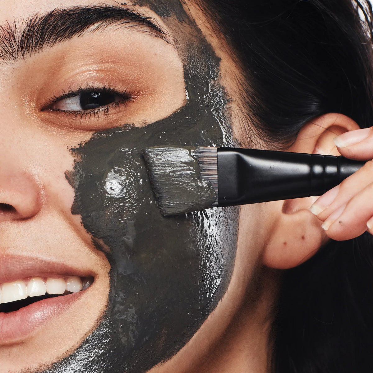 Woman applying The Dead Sea Co.'s mineral mask using an angled brush for precise application.