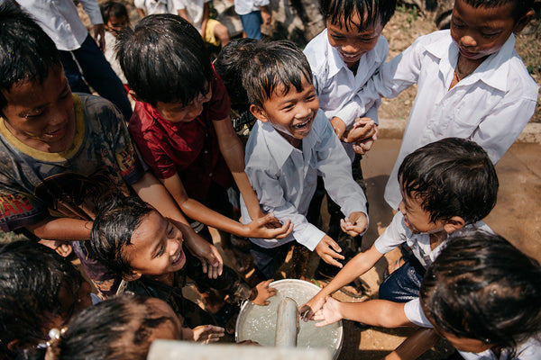 Niños rellenando un cubo de agua de un pozo construido por AUARA en Camboya