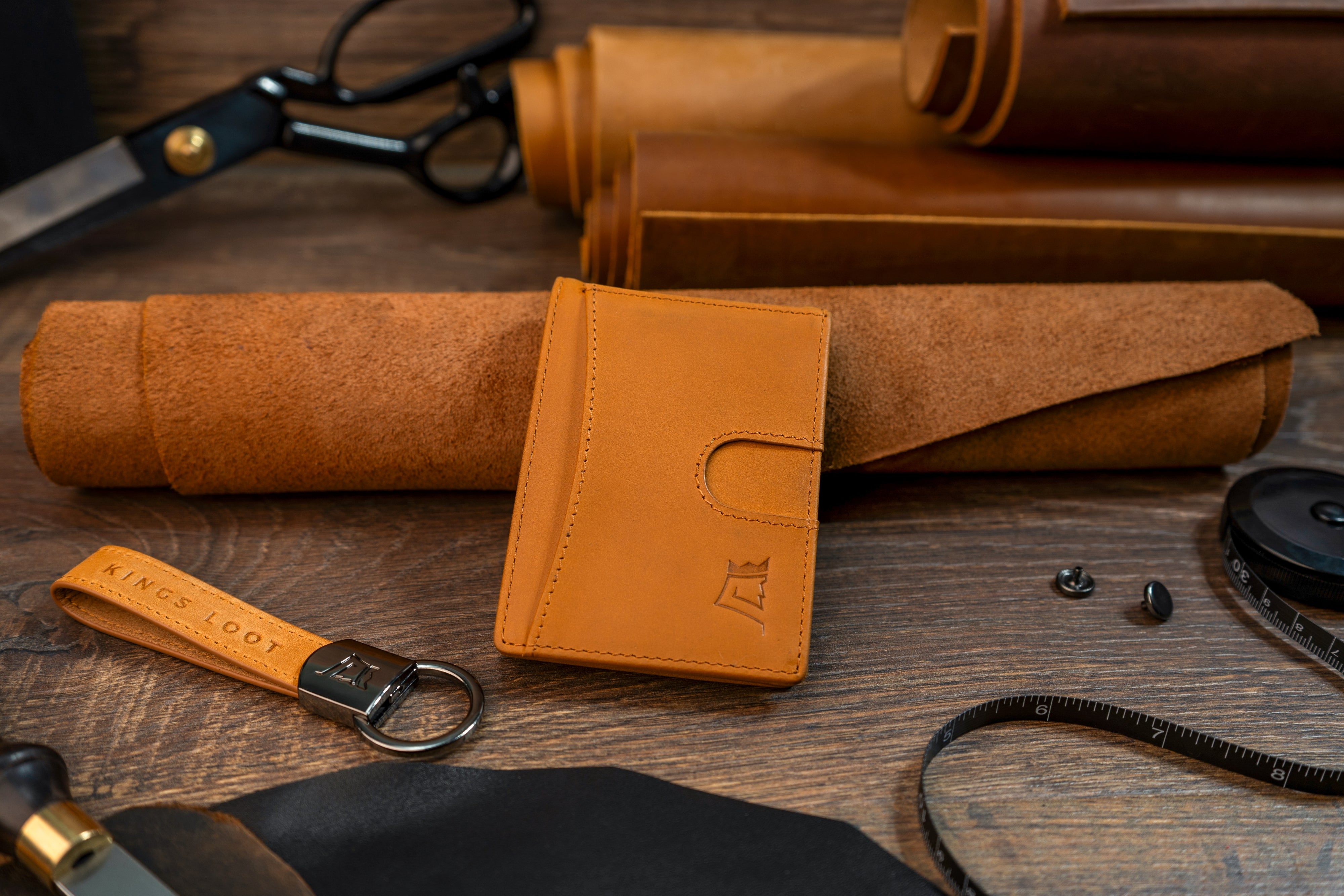 Leather wallet, keychain, rolled pouches, and accessories on a wooden surface.
