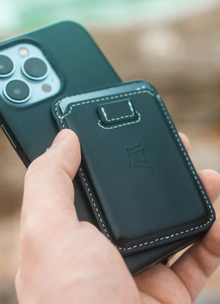 Hand holding a smartphone with a black leather case and camera cutout.