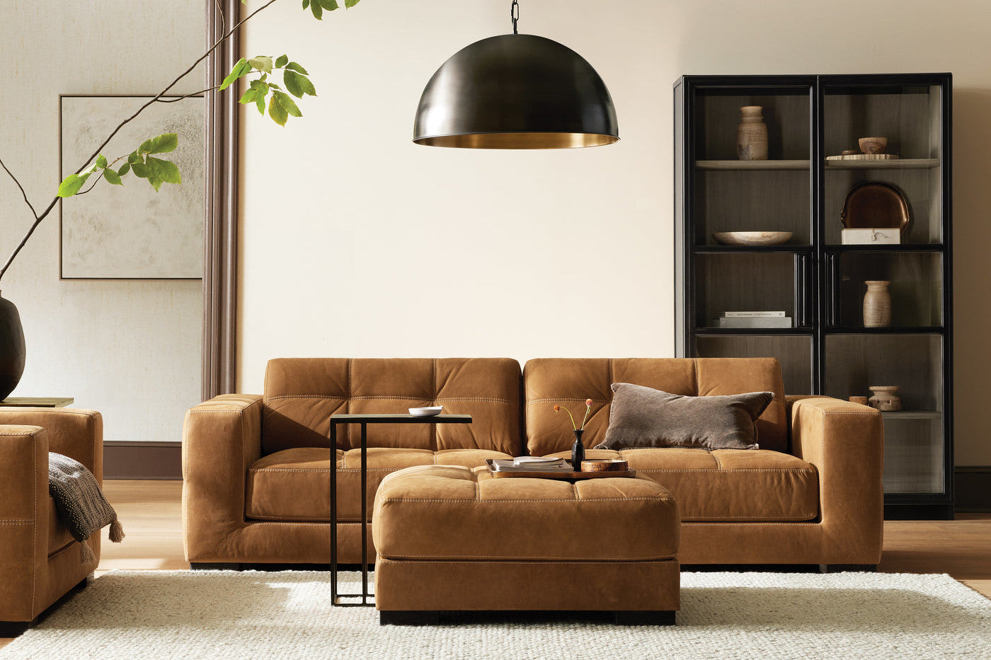 Brown leather sofa with black cabinet and large black pendant light